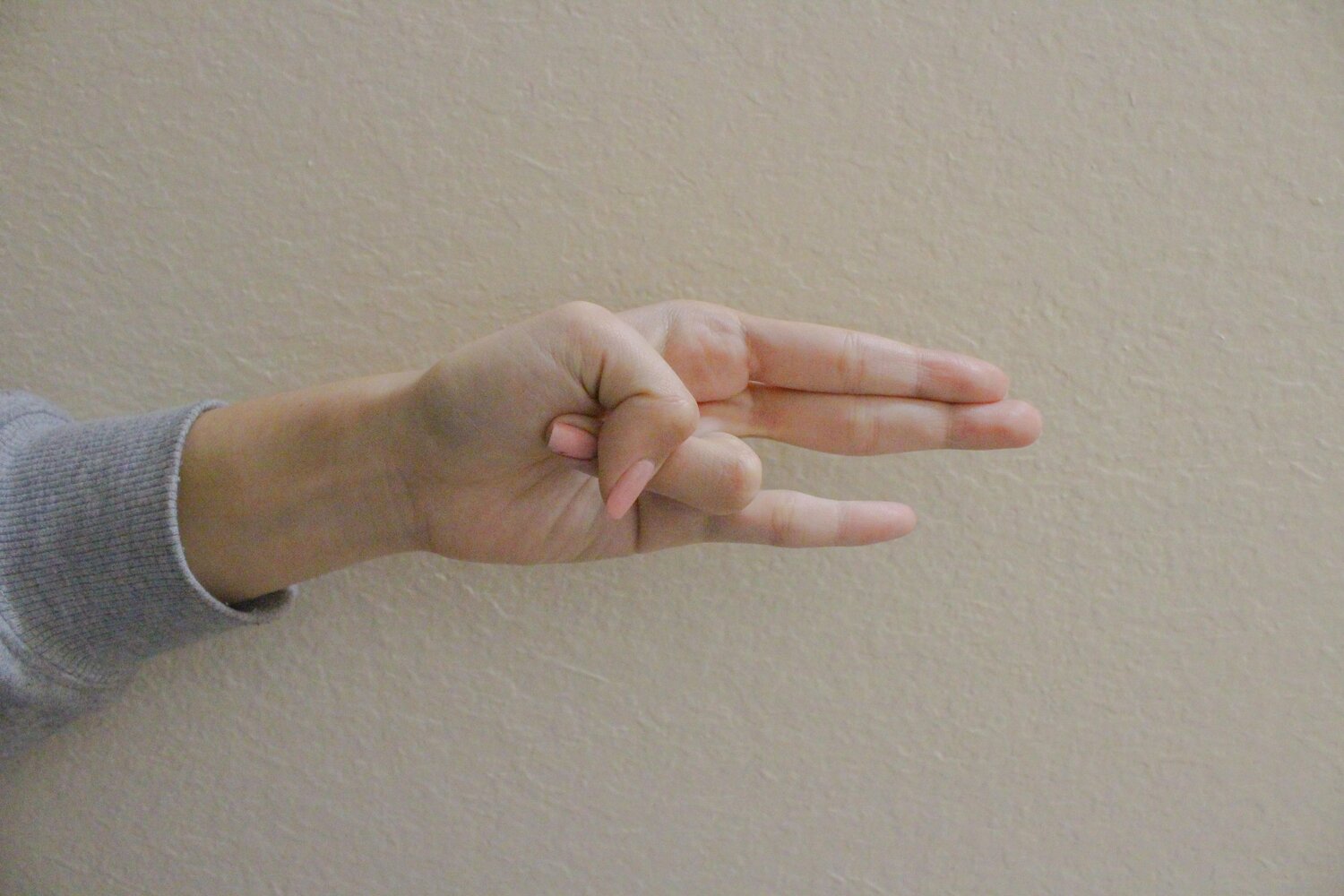 Thumb holding the ring finger while the rest of the fingers point outwards